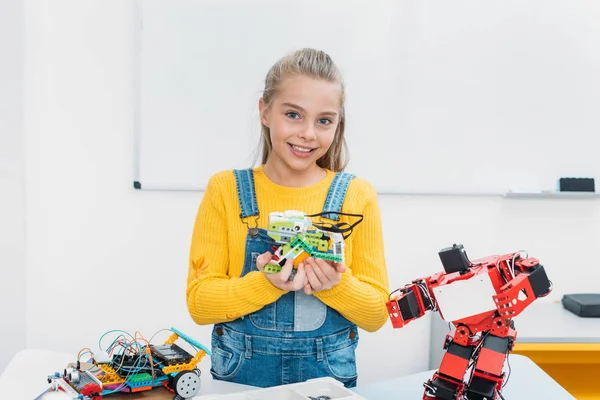 Щасливі школярка, дивлячись на камеру і представляти ручної роботи робот модель в стовбурових урок — стокове фото