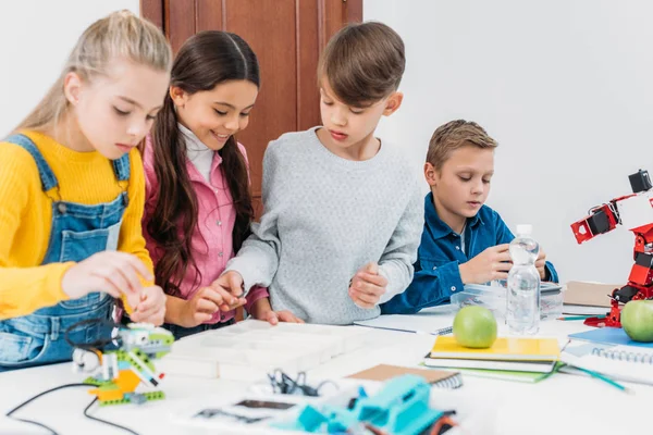 Niños enfocados trabajando juntos en el proyecto STEM en clase - foto de stock