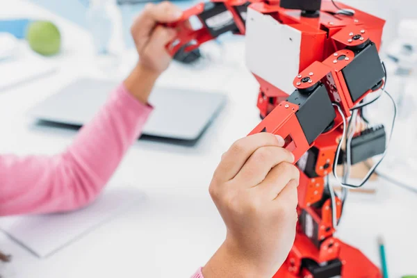 Partial view of schoolkid playing with robot model during STEM lesson — Stock Photo