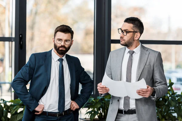 Serious businessmen standing together and discussing project in office — Stock Photo
