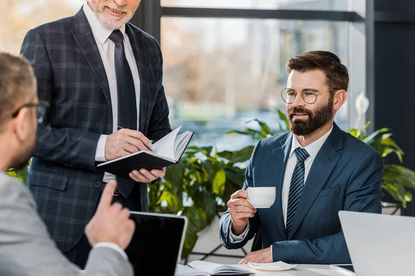 Recortado disparo de sonrientes hombres de negocios trabajando juntos en la oficina - foto de stock