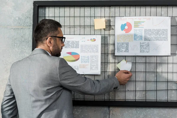 Back view of businessman working with charts and graphs in office — Stock Photo