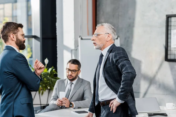 Side view of businessmen talking while standing in office — Stock Photo