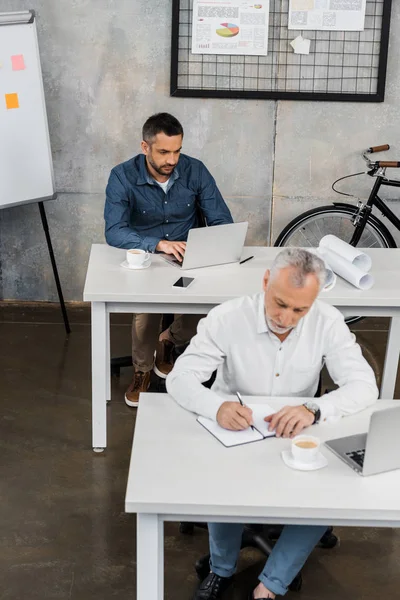 High angle view of businessmen sitting at tables and working in office — Stock Photo