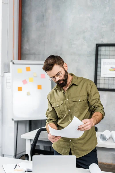 Handsome bearded businessman reading documents in office — Stock Photo