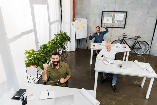 High angle view of happy handsome businessmen showing yes gesture in office — Stock Photo