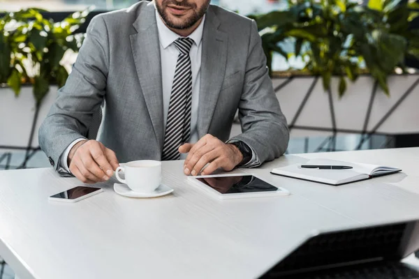 Geschnittenes Bild eines Geschäftsmannes, der eine Tasse Kaffee am Tisch im Büro einnimmt — Stockfoto