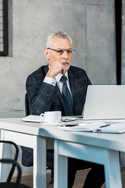 Schöner Geschäftsmann mittleren Alters arbeitet am Laptop im Büro — Stockfoto