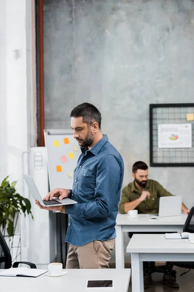 Zwei hübsche Geschäftsleute, die im Büro an Laptops arbeiten — Stockfoto