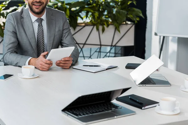 Immagine ritagliata di uomo d'affari che tiene tablet a tavola in ufficio — Foto stock