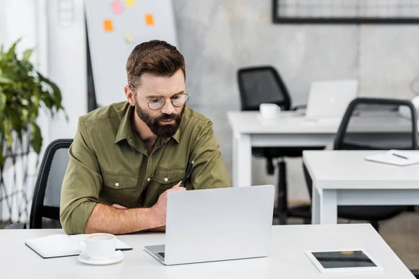 Schöner Geschäftsmann mit Blick auf Laptop im Büro — Stockfoto