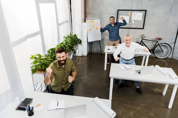 High angle view of excited handsome businessmen showing yes gesture in office — Stock Photo