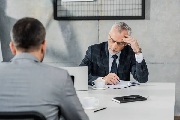 Nachdenkliche Geschäftsleute sitzen im Büro am Tisch — Stockfoto