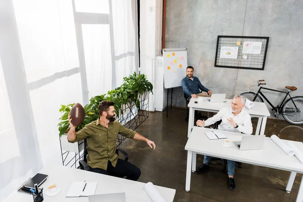 Vista de ángulo alto de hombres de negocios guapos que se divierten en la oficina - foto de stock