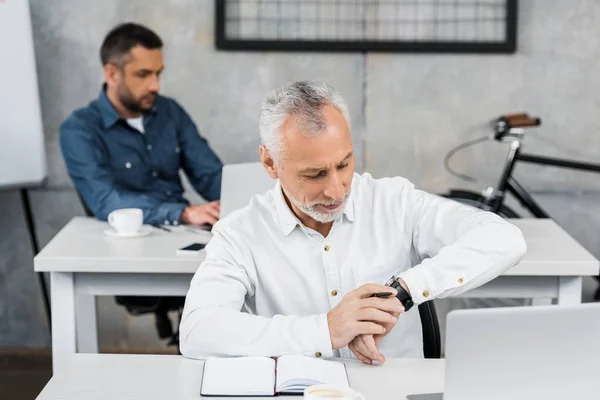 Bell'uomo d'affari che controlla il tempo sull'orologio da polso in ufficio — Foto stock