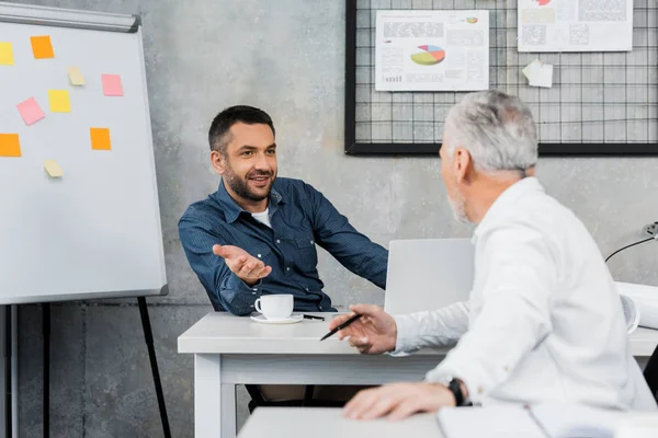 Two handsome businessmen talking and gesturing in office — Stock Photo