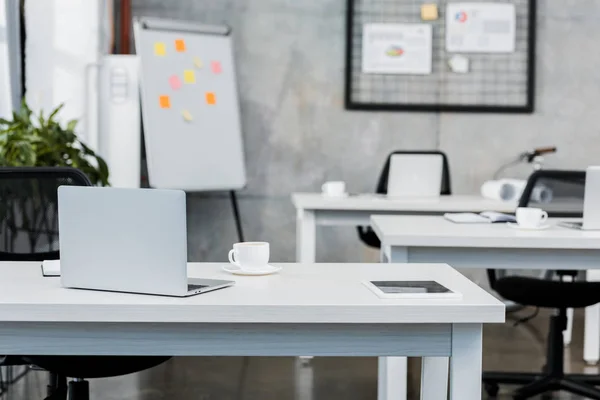 Cup of tea and laptop on table in office — Stock Photo