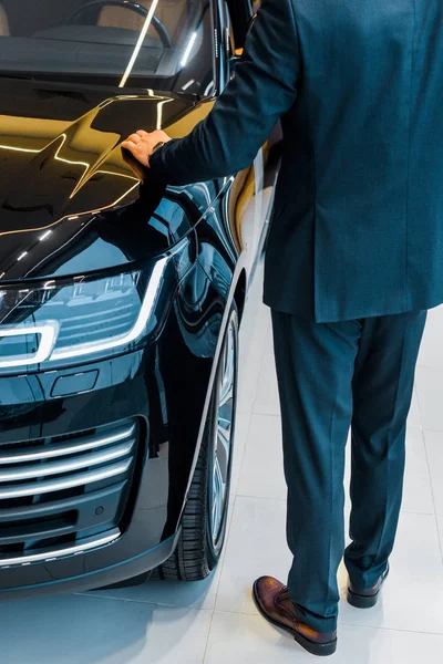 Обрезанный образ бизнесмена, выбирающего автомобиль в салоне автосалона — стоковое фото