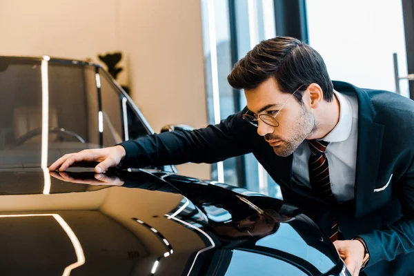 Focused businessman in eyeglasses choosing automobile in dealership salon — Stock Photo