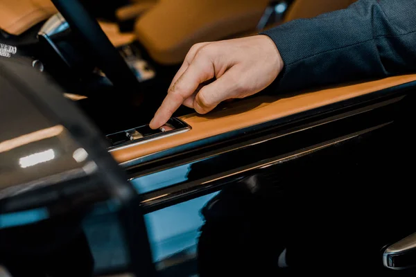 Cropped image of businessman pushing button for closing window of automobile — Stock Photo