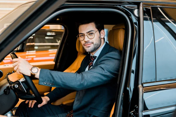 Glücklicher stylischer Geschäftsmann mit Brille sitzt im Luxusauto — Stockfoto