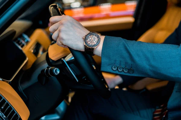 Cropped image of businessman with luxury watch sitting in automobile — Stock Photo