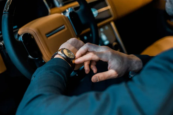 Cropped image of businessman checking watch in luxury car — Stock Photo