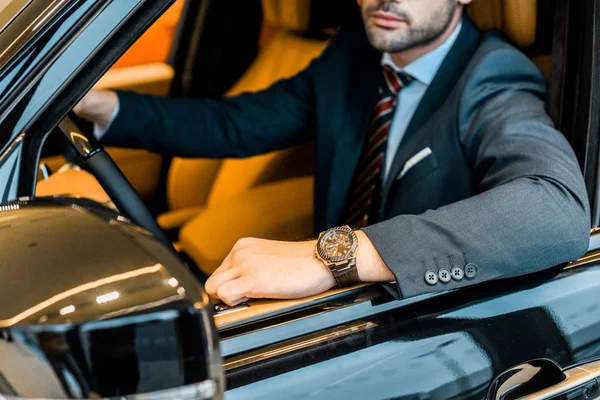 Vue partielle de l'homme d'affaires avec montre de luxe assis dans l'automobile — Photo de stock