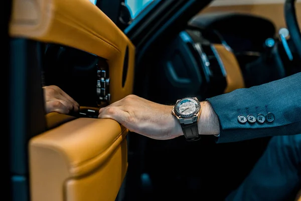 Imagen recortada de hombre de negocios con la puerta de cierre de reloj de lujo mientras está sentado en el coche - foto de stock