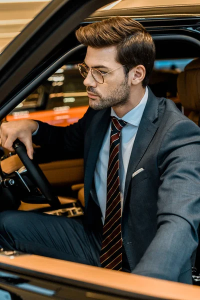 Stilvoller junger Geschäftsmann schließt Tür, während er im Auto sitzt — Stockfoto