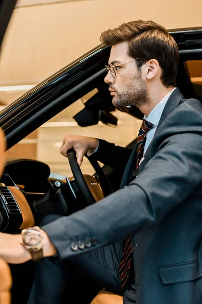 Side view of businessman with luxury watch closing door while sitting in car — Stock Photo