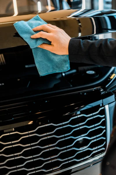 Cropped image of businessman cleaning car hood with rug — Stock Photo