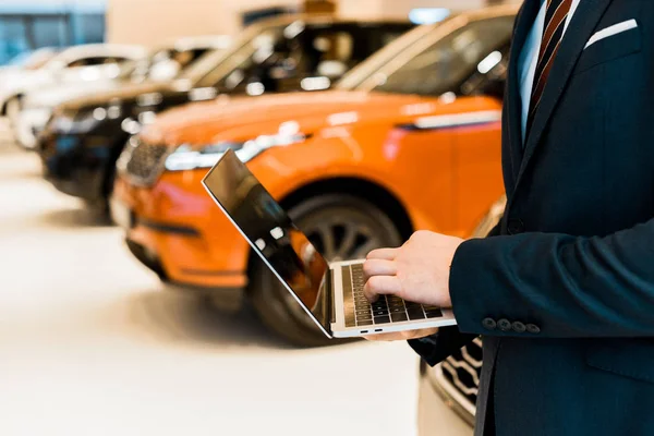 Abgeschnittenes Bild eines Geschäftsmannes im formellen Anzug mit Laptop im Autohaus-Salon — Stockfoto