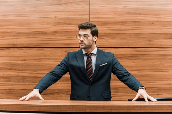 Confident young businessman in eyeglasses standing at reception of modern office — Stock Photo