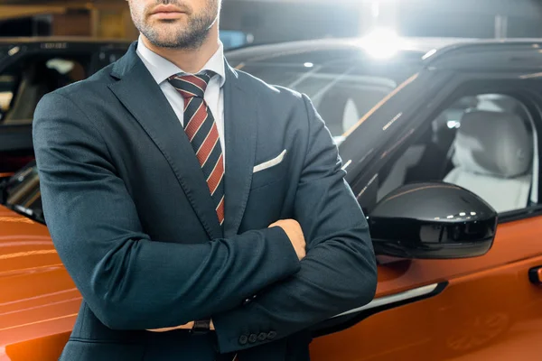 Partial view of businessman posing with crossed arms near automobile — Stock Photo