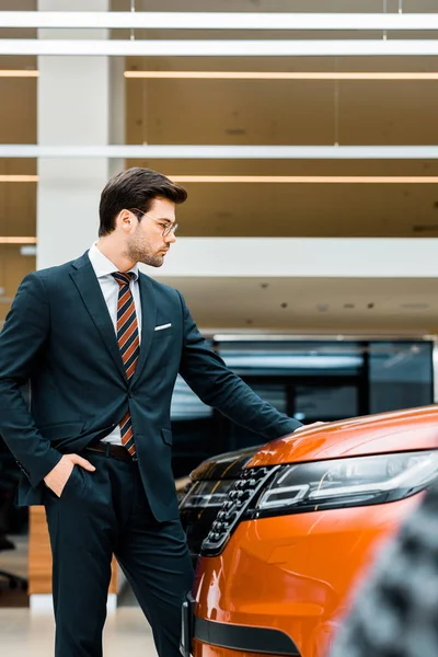 Side view of handsome businessman in eyeglasses choosing car in dealership salon — Stock Photo