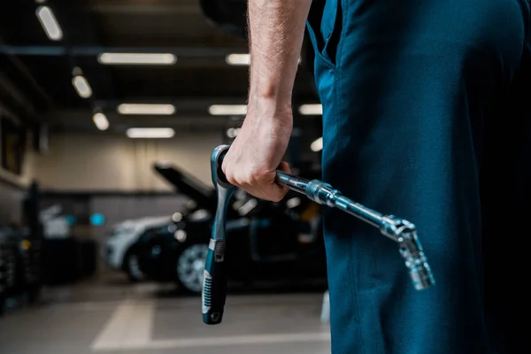 Partial view of auto mechanic holding lug wrench at mechanic shop — Stock Photo