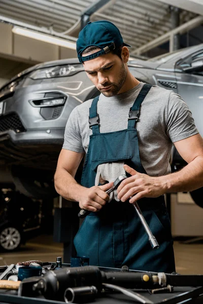Retrato de mecánico de automóviles en uniforme con llave inglesa en taller de reparación de automóviles - foto de stock
