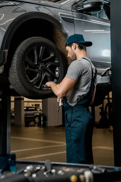 Meccanico auto in uniforme fissaggio ruota auto presso officina auto — Foto stock