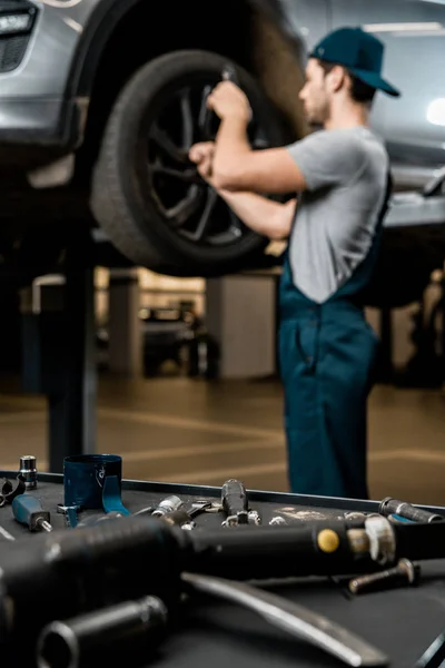 Enfoque selectivo de mecánico de automóviles en la fijación uniforme de la rueda del coche en taller de reparación de automóviles - foto de stock