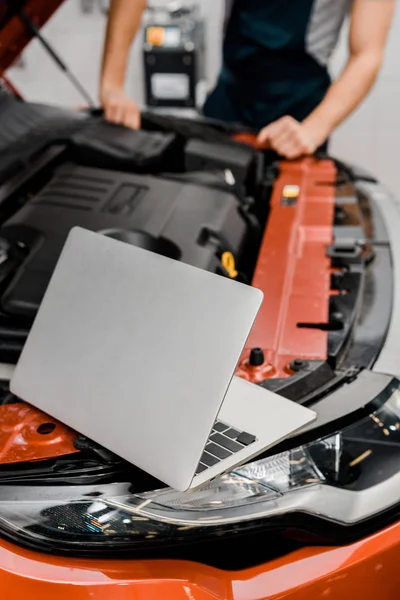 Messa a fuoco selettiva del computer portatile e meccanico auto in officina di riparazione auto — Foto stock