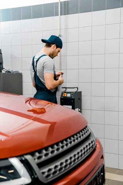 Young auto mechanic in uniform at mechanic shop — Stock Photo