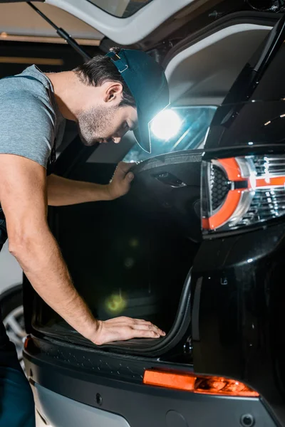 Зосереджений автомеханік перевіряє автомобільний багажник в авторемонтному магазині — стокове фото