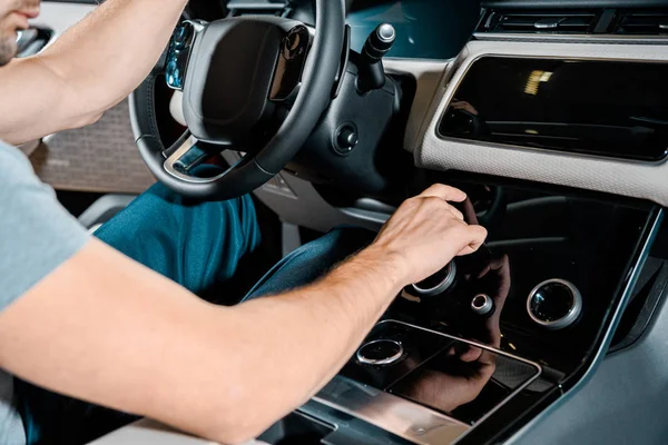 Cropped shot of mechanic sitting on drivers seat and checking automobile details — Stock Photo