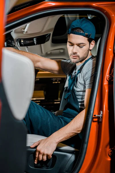 Side view of auto mechanic sitting on drivers seat in car — Stock Photo