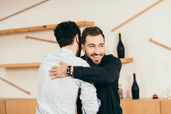 Amigos abrazándose mientras se saludan en la cafetería — Stock Photo