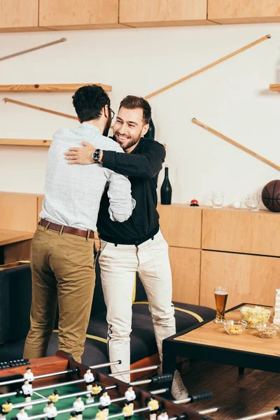 Друзья обнимаются, приветствуя друг друга в кафе — стоковое фото