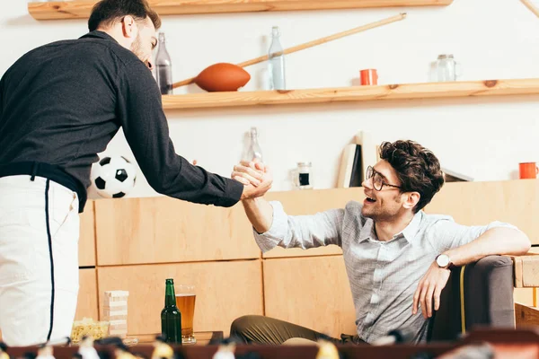 Homens felizes apertando as mãos enquanto cumprimentam uns aos outros no café — Fotografia de Stock