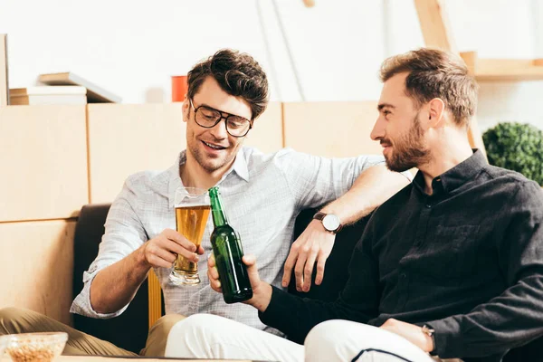 Amigos sonrientes tintineo de vidrio y botella de cerveza en la cafetería - foto de stock