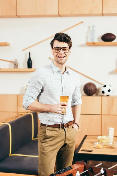 Ritratto di uomo sorridente in occhiali con bicchiere di birra in mano nel caffè — Foto stock